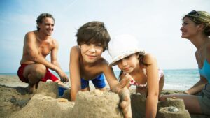 a family of four playing in the sand building a sandcastle with ocean in the background in Myrtle Beach, South Carolina, USA